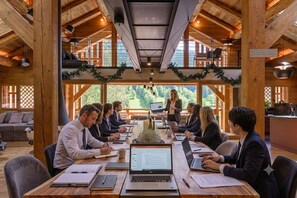 A conference room with wooden beams, a high ceiling, and a large window overlooking greenery. - New Listing (La Clusaz)