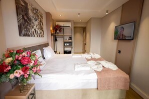 A hotel room with a large bed, a television mounted on the wall, and a floral arrangement on the side table. - The Diamond City Hotel Yenikapi (Fatih)