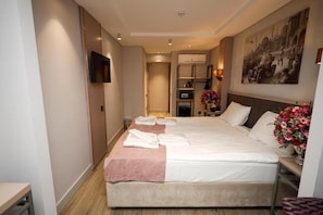 A hotel room with a large bed, a television, a painting on the wall, and a hallway leading to a bathroom. - The Diamond City Hotel Yenikapi (Fatih)
