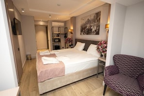A hotel room with a bed, a chair, a painting on the wall, and a small table with a lamp. - The Diamond City Hotel Yenikapi (Fatih)