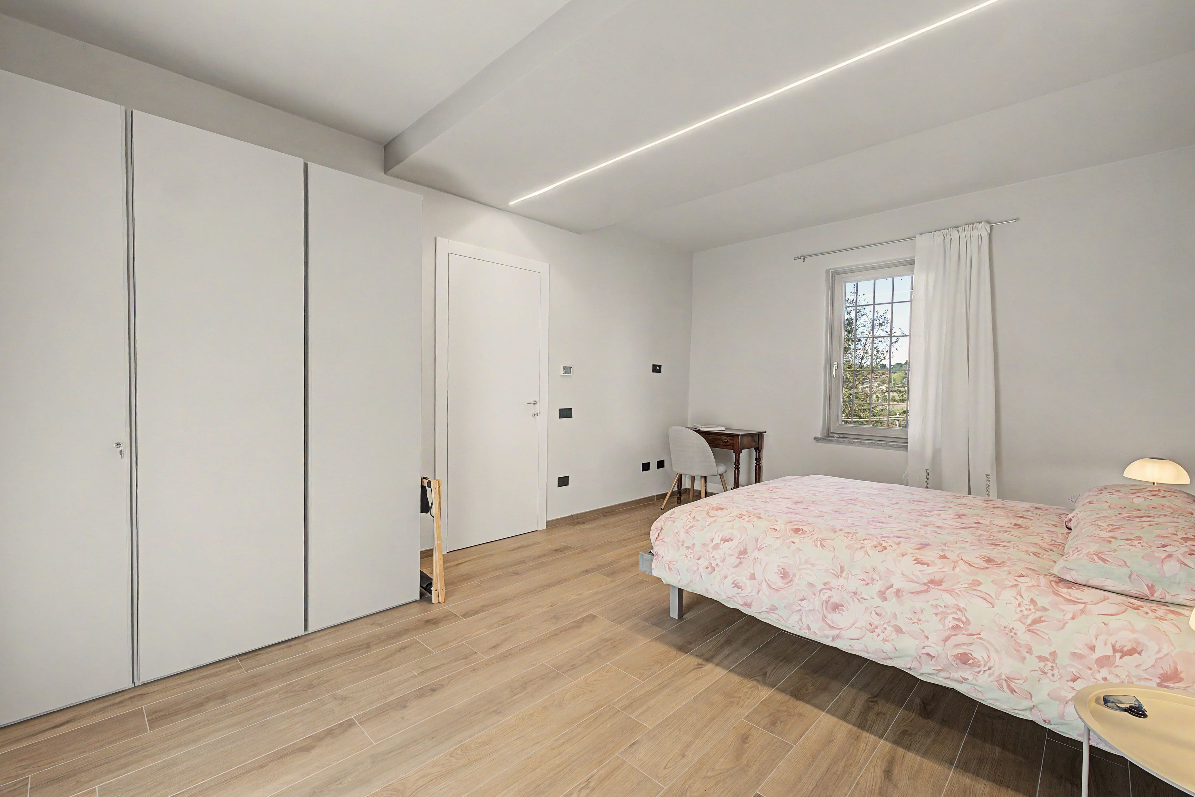 Una camera da letto con un letto, una scrivania, una sedia e un armadio.
