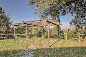 Una pergola in legno in un parco, circondata da erba e alberi.