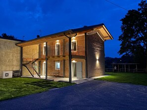 Un edificio a due piani con una scala che conduce al piano superiore, un balcone e un ingresso ben illuminato.