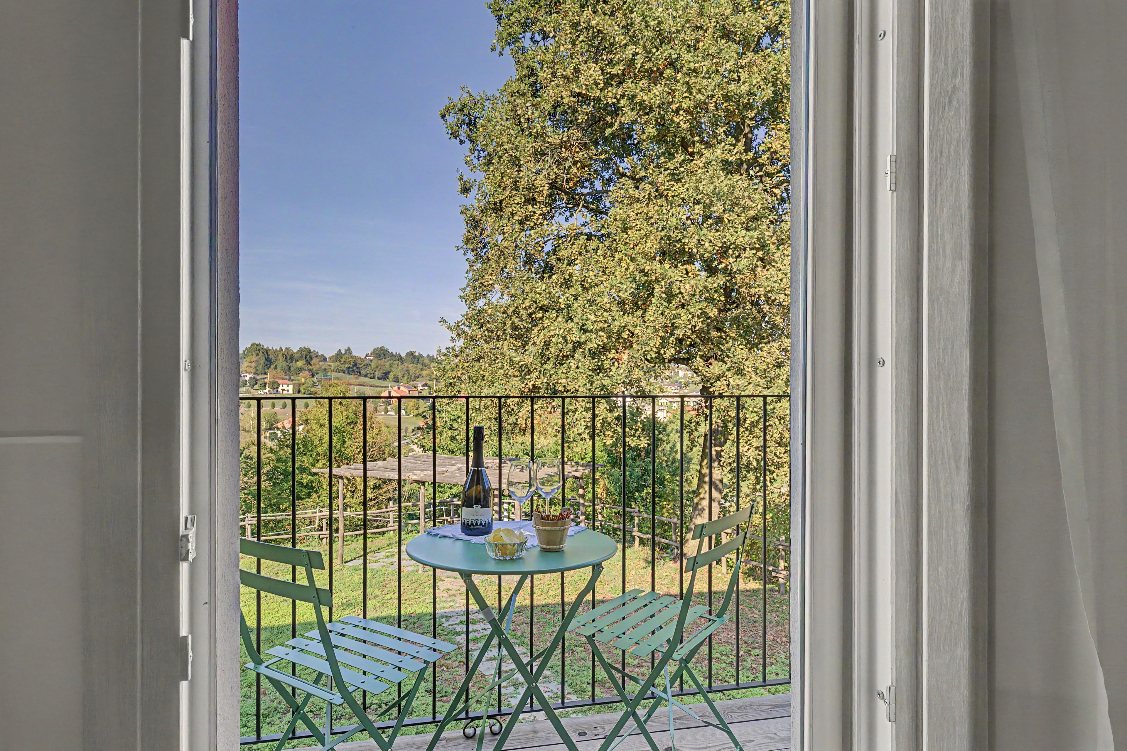 Un balcon avec une table, des chaises, une bouteille et des verres.