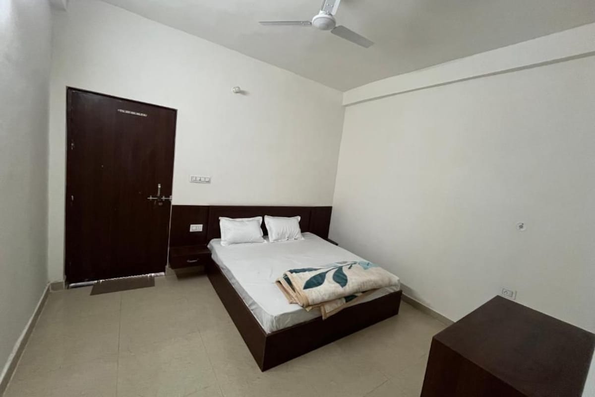 A bedroom with a bed, a wardrobe, a bedside table, and a ceiling fan.