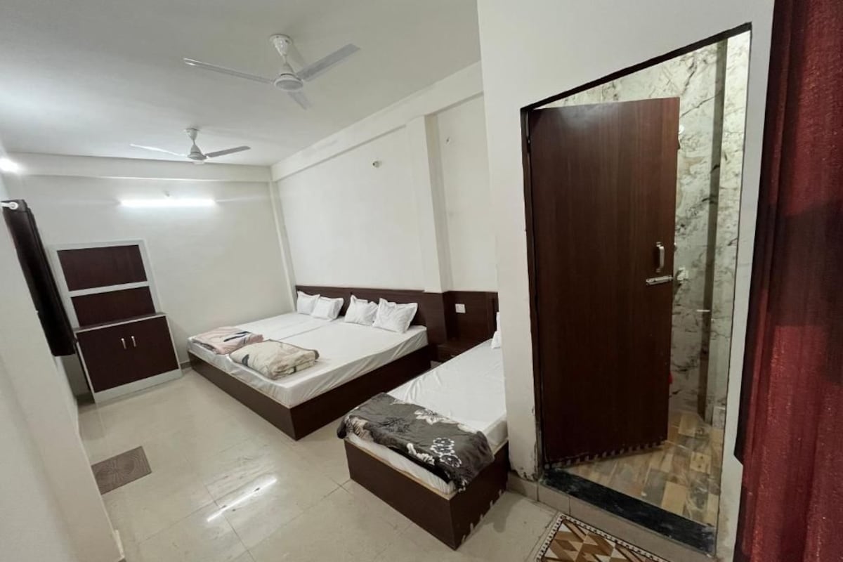 A bedroom with a bed, a wardrobe, a small bench, a ceiling fan, and a door with a glass panel.