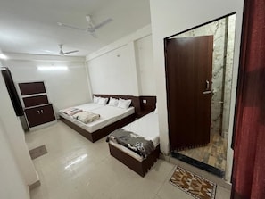 A bedroom with a bed, a wardrobe, a small bench, a ceiling fan, and a door with a glass panel. - Hotel dayalu palace (Vrindavan)