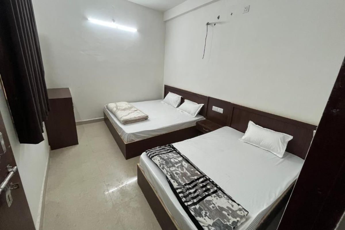 A hotel room with two beds, a wardrobe, and a wall-mounted light fixture.
