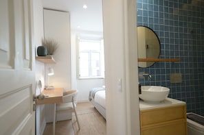 Une chambre à coucher avec un lit, une table de chevet et une fenêtre.