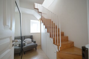 A modern interior with a staircase, a grey upholstered chair, and a wooden floor. - New Listing (Lisboa)