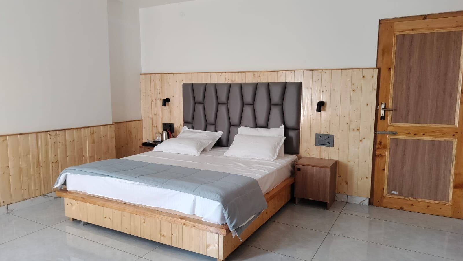 A bedroom with a wooden bed frame, a headboard, a bedside table, and a wardrobe.