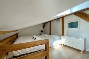 Quarto com cama de madeira, mesa de cabeceira branca e um quadro na parede.