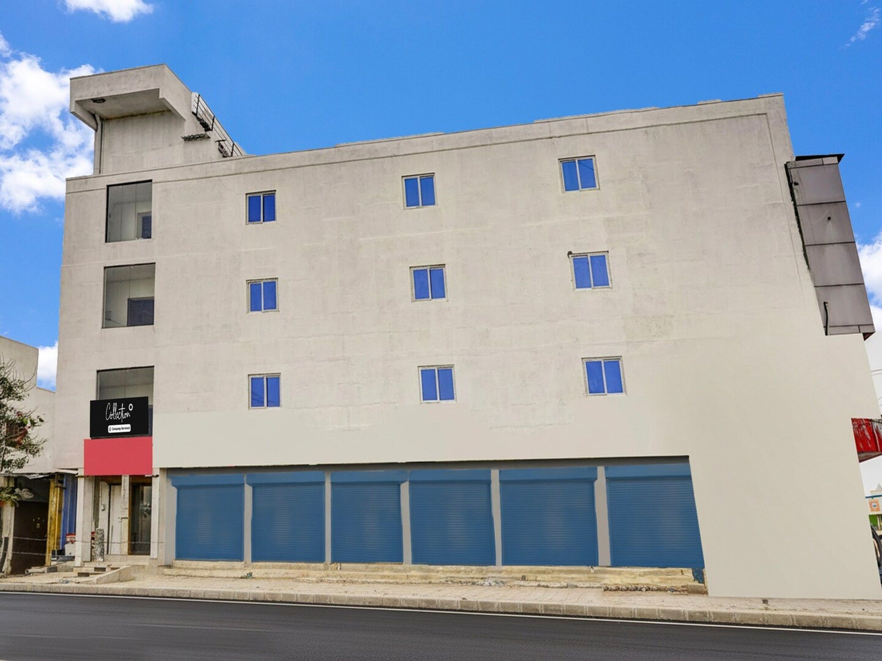 A multi-story building with a flat facade, several windows, and a ground-level garage.