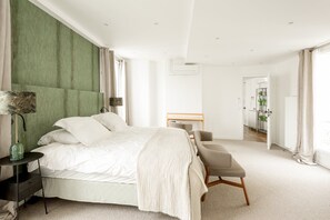 Quarto moderno com uma cama grande, mesas de cabeceira, escrivaninha e vista para o corredor.