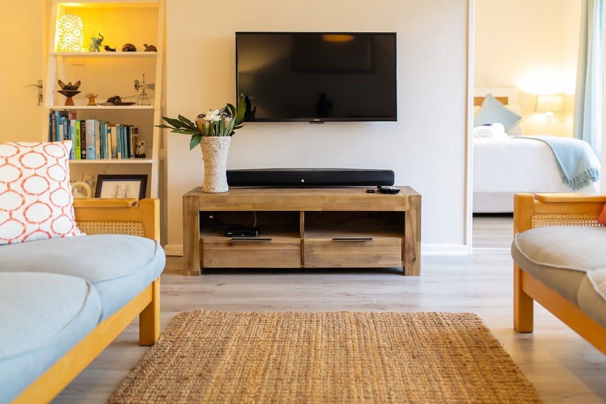 A modern living room with a flat-screen TV, wooden entertainment unit, and two sofas.