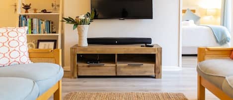 A modern living room with a flat-screen TV, wooden entertainment unit, and two sofas.