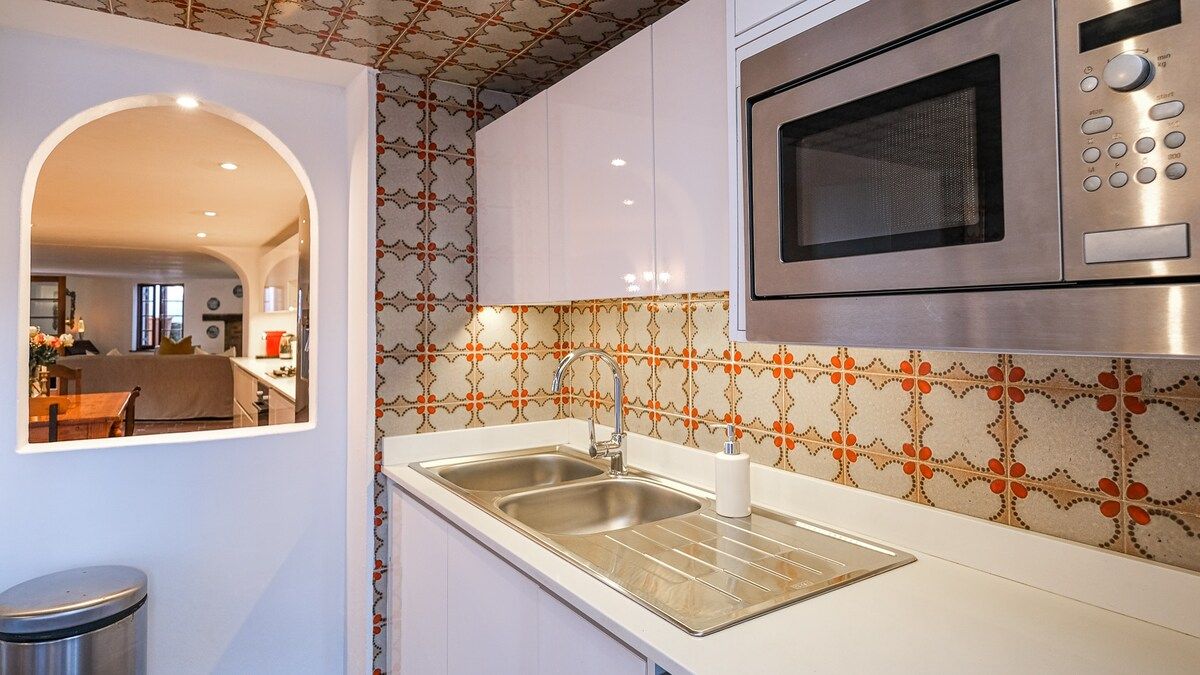 Una cocina con un lavaplatos doble, electrodomésticos de acero inoxidable y un salpicadero con diseño.