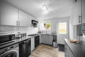 A modern kitchen with white cabinets, stainless steel appliances, and a wooden floor. - Whole House In The Yorkshire Dales Near Harrogate (Dacre Banks)