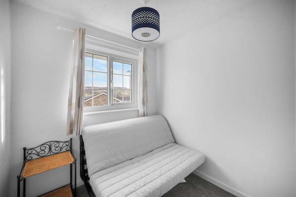 A room with a bed, a window, a ceiling light fixture, and a small table with a chair. - Whole House In The Yorkshire Dales Near Harrogate (Dacre Banks)