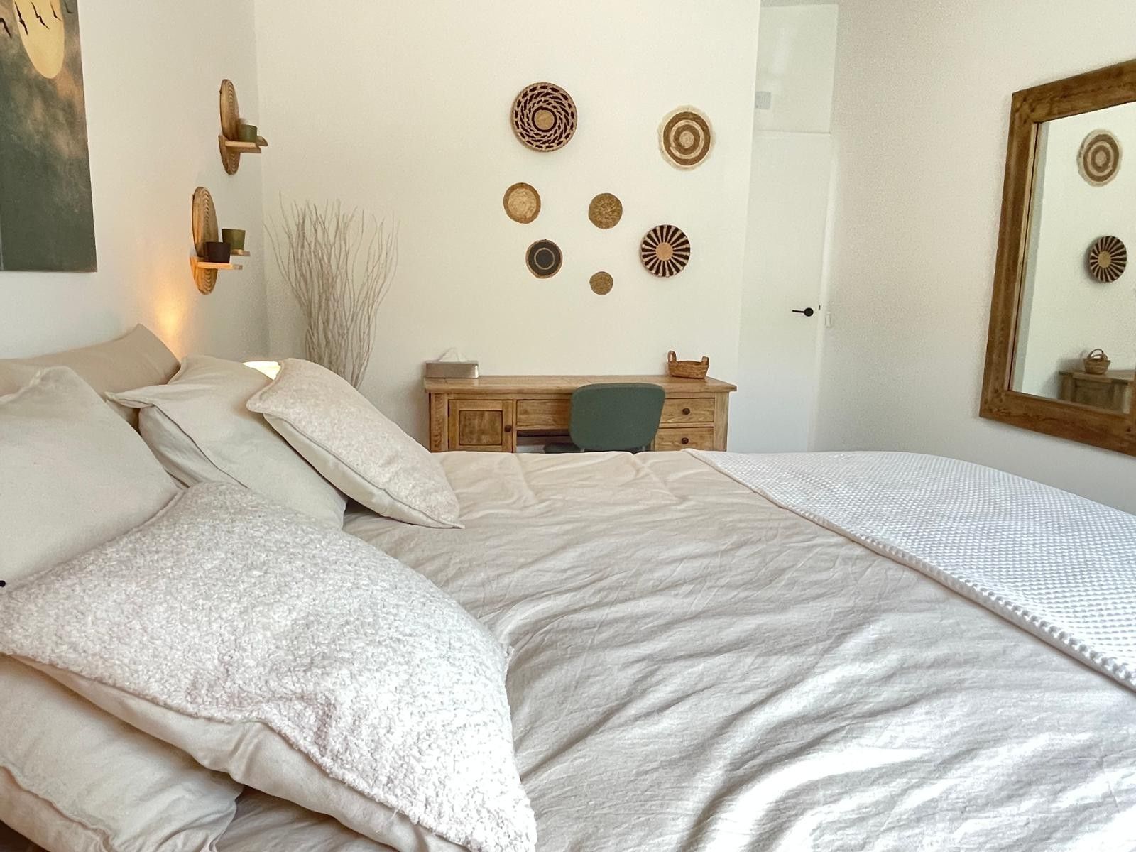 Un dormitorio con cama, cómoda, silla y decoración en la pared.