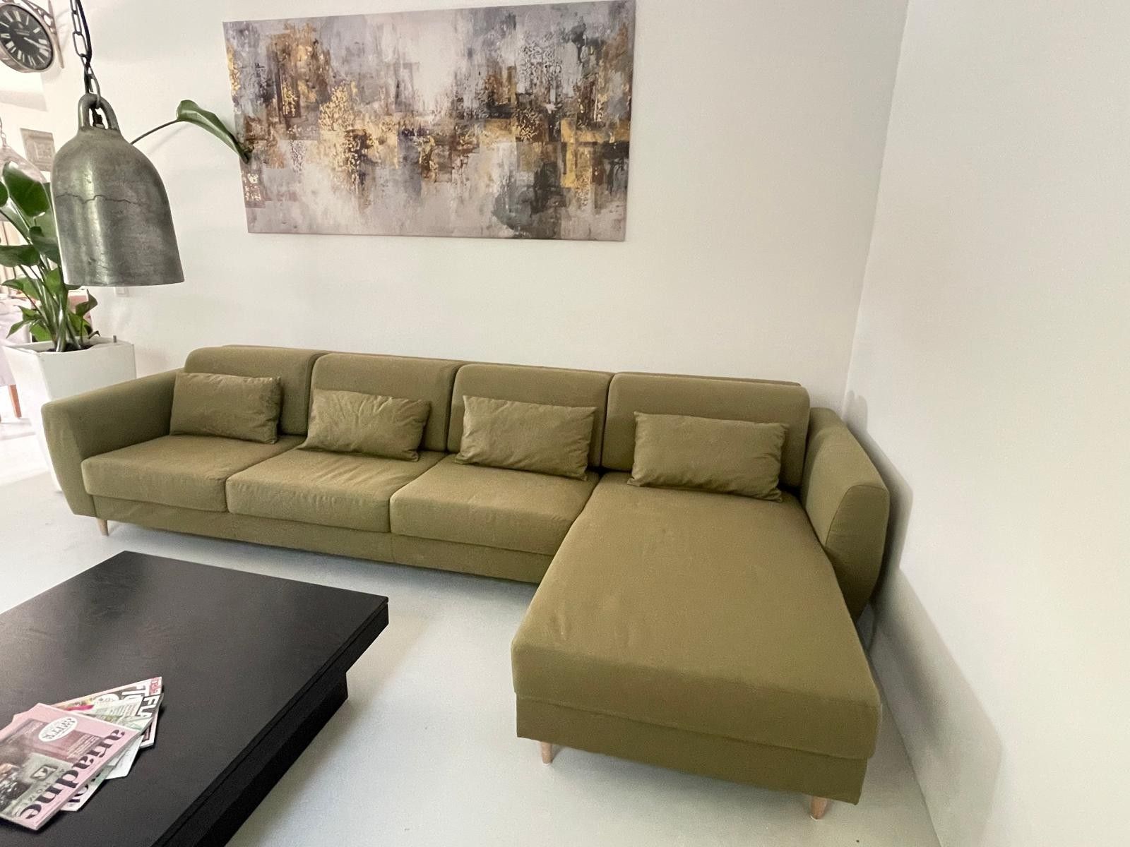 Un sofá modular con una mesa de centro negra, un reloj de pared y un cuadro.