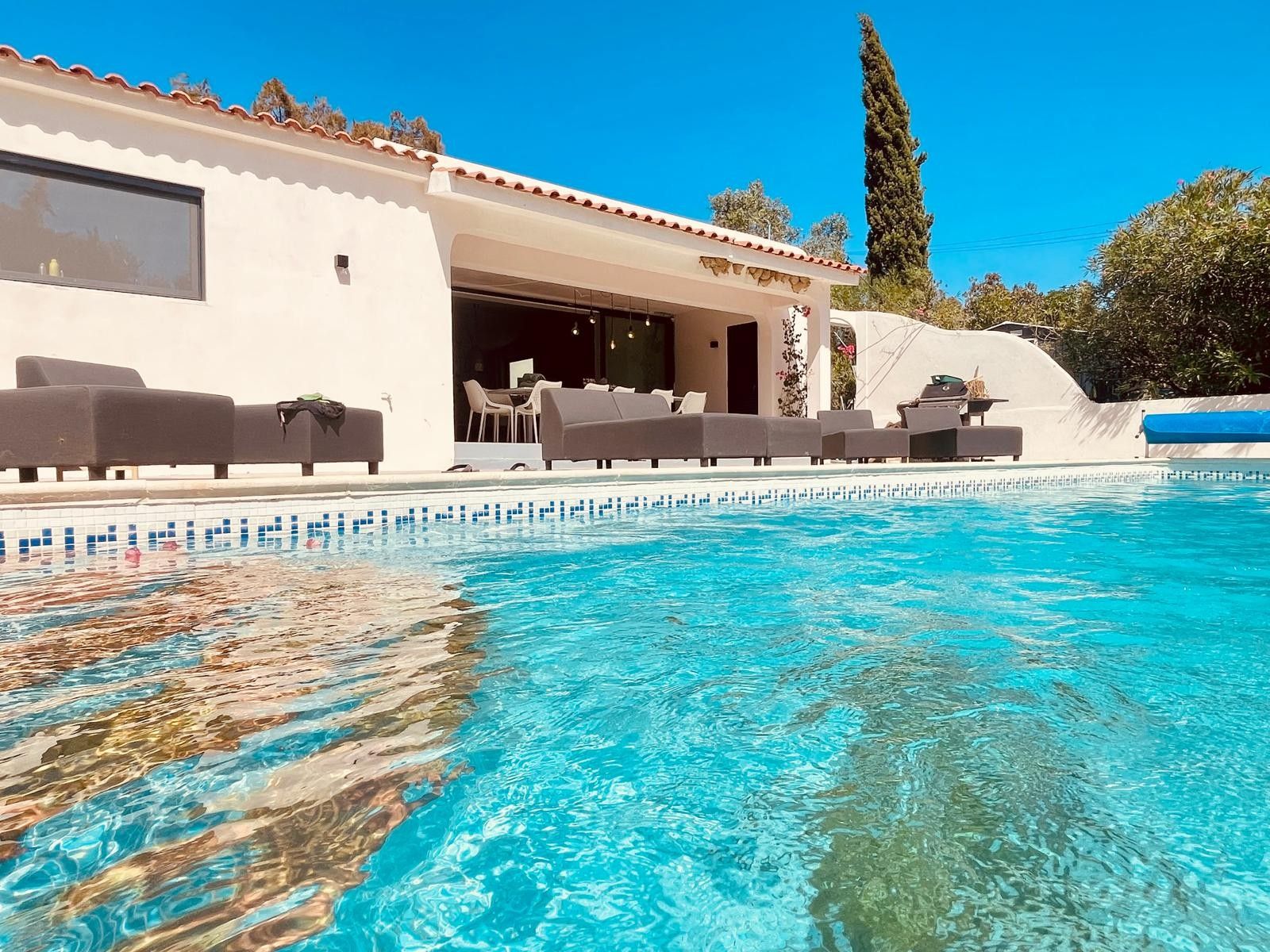 Un espace piscine avec des chaises longues et un coin salon abrité.