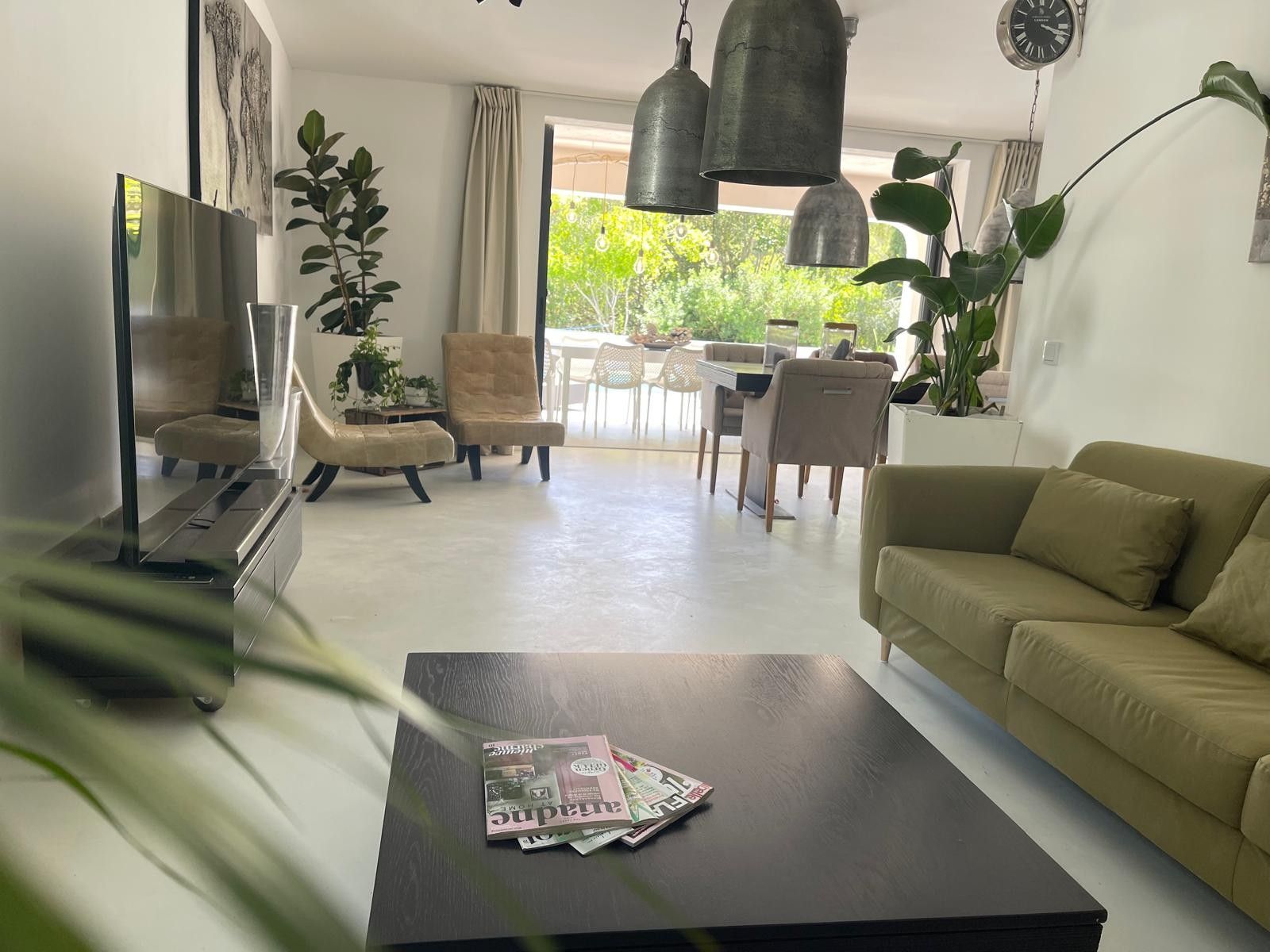 Un salon moderne comprenant un canapé, une table basse avec des magazines, un téléviseur et un coin repas avec des chaises et une table.