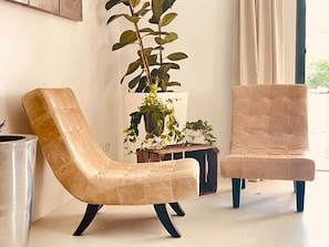 Una habitación con dos sillones de cuero, una planta en maceta y una mesita.