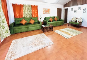 A living room with two green sofas, a coffee table, and a patterned rug. - Casa Santorini by Roamvacay (Kashele)