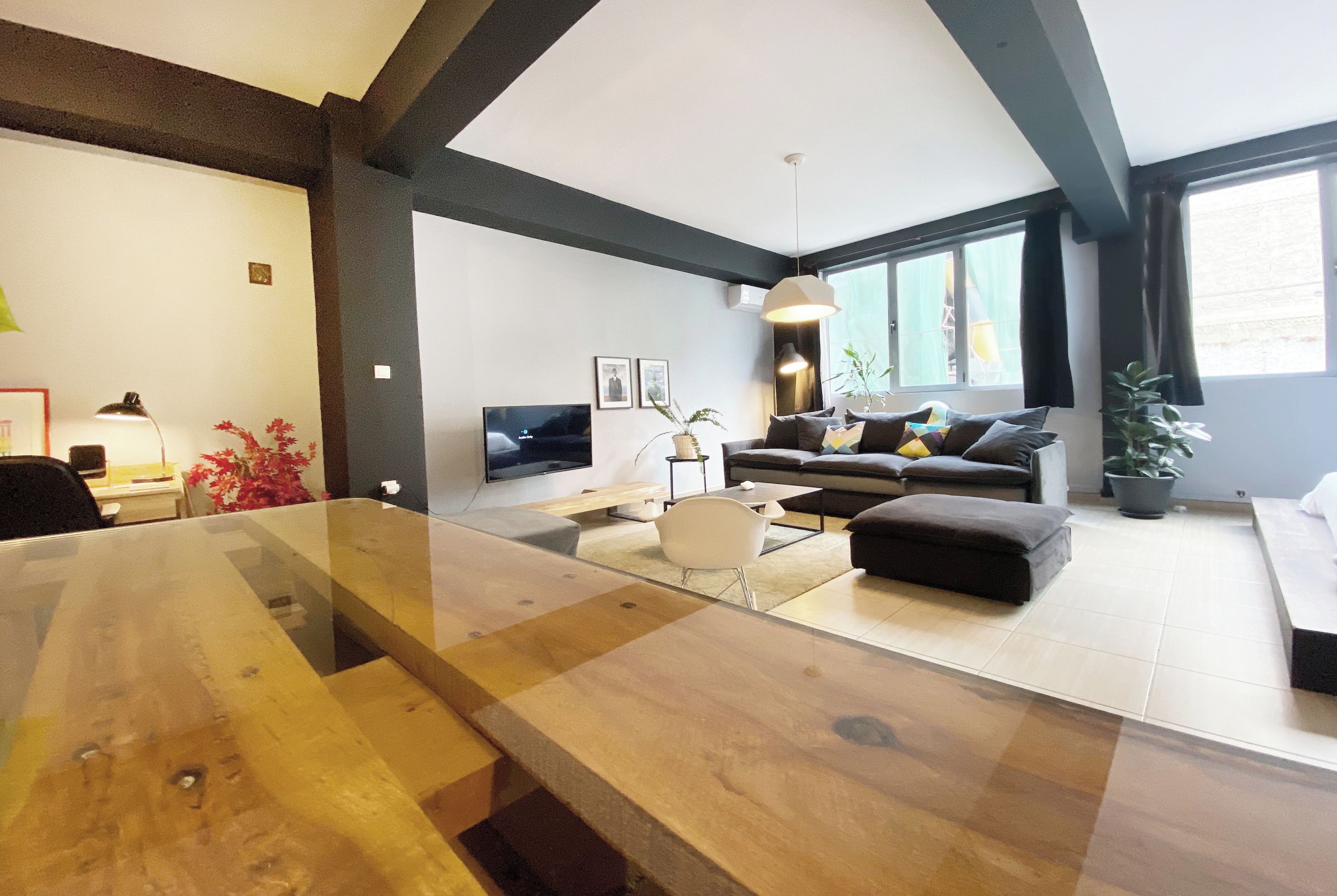 A modern living room with a wooden dining table, a sofa, and a TV.