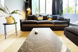 A modern living room with a sofa, a coffee table, and a side table with a plant. - Live in Athens Psyrri Lively Apartments (Athina)