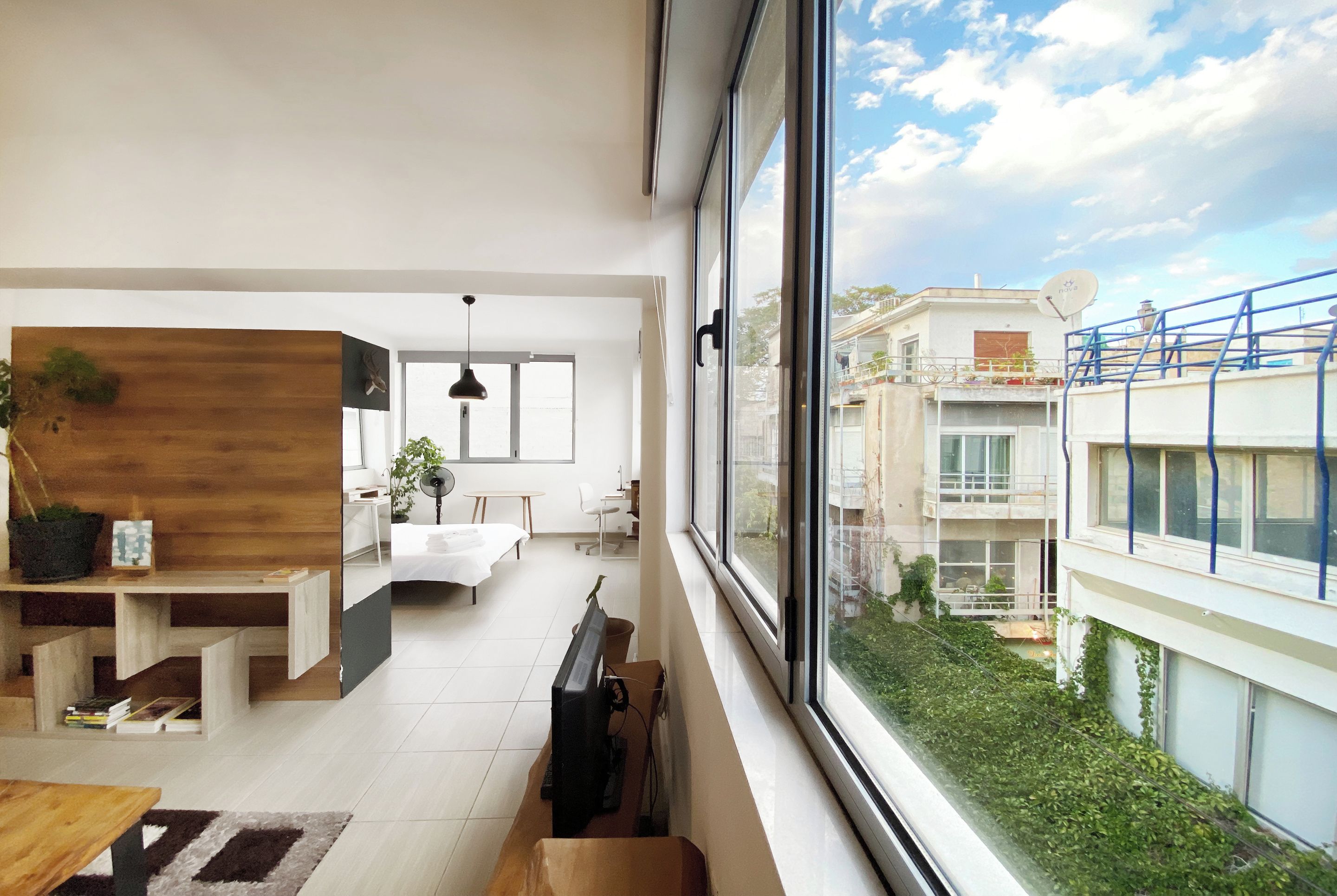 A modern interior with a dining area, a kitchen, and a large window offering a view of the cityscape.