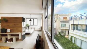 A modern interior with a dining area, a kitchen, and a large window offering a view of the cityscape.