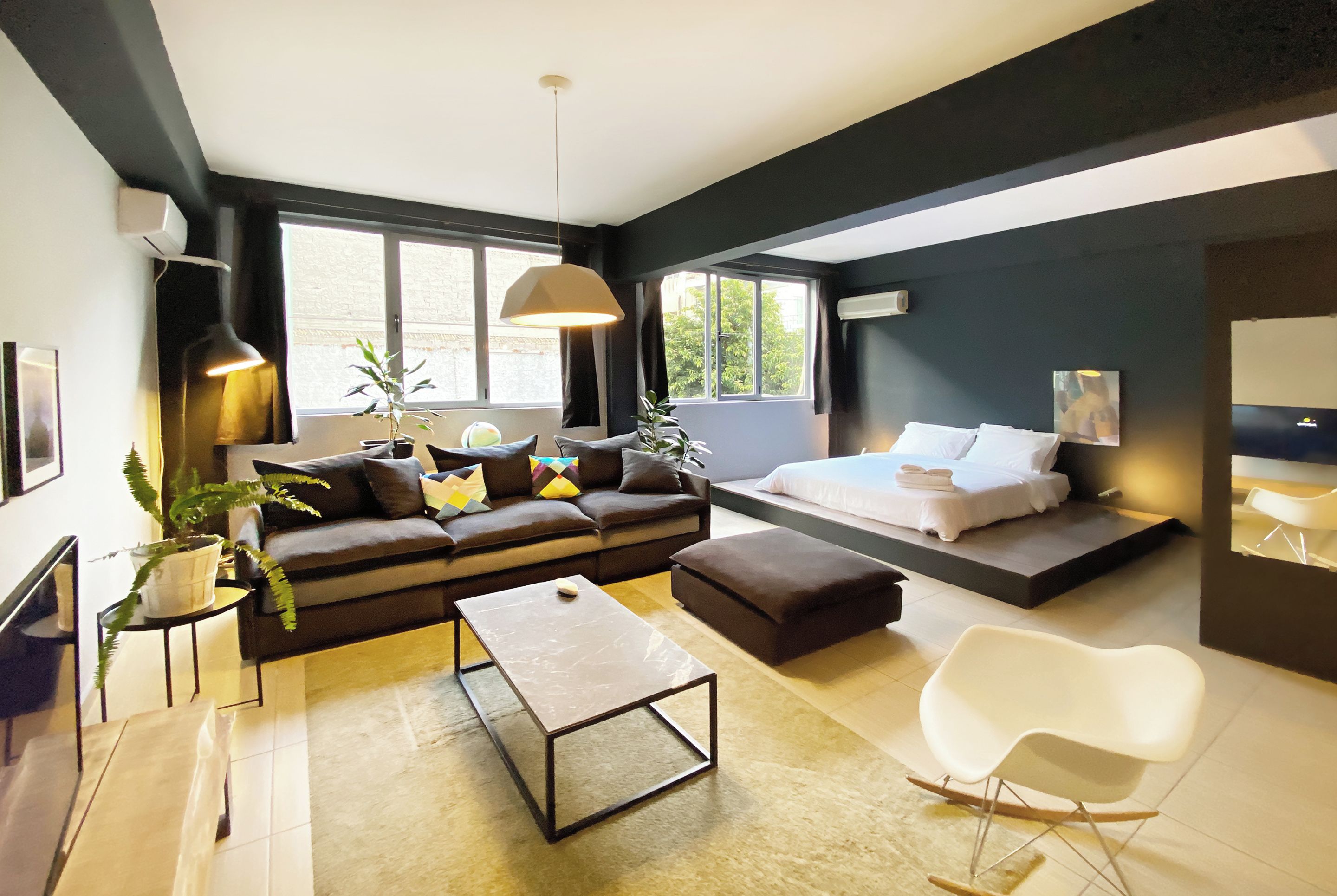 Un salon moderne avec un canapé, une table basse et un lit doté d’un matelas blanc.