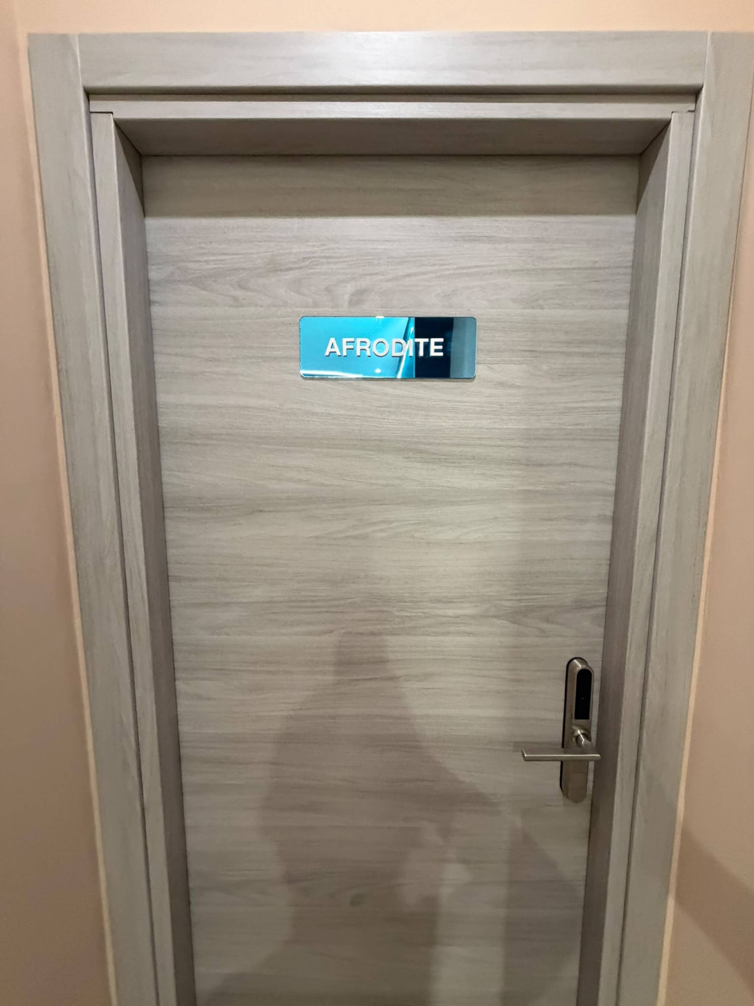 Eine Tür mit einem Schild, auf dem 'AFRODITE' steht, und einem Metallgriff.