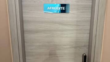 Eine Tür mit einem Schild, auf dem 'AFRODITE' steht, und einem Metallgriff.
