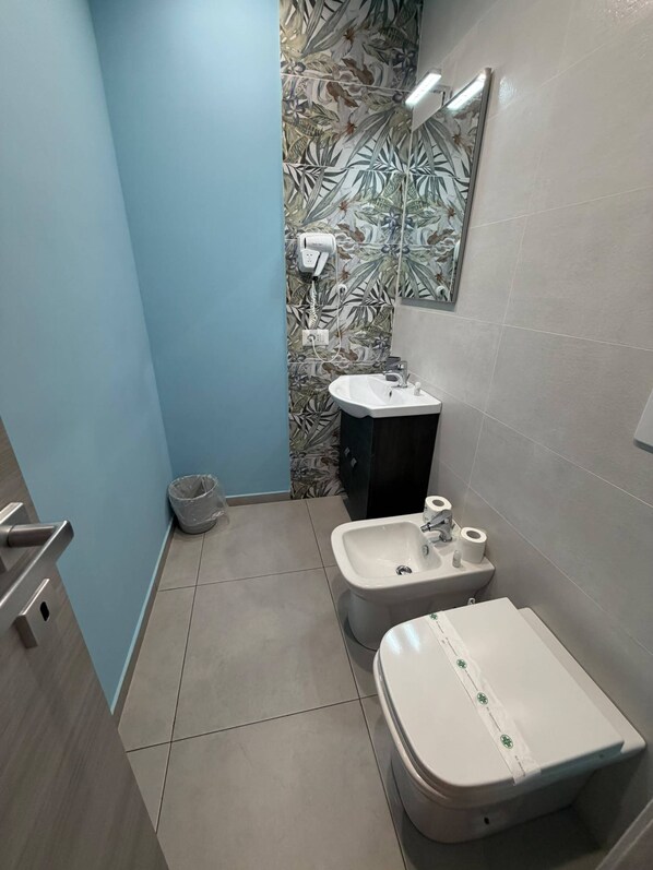 Un bagno con il water, bidet e lavandino.