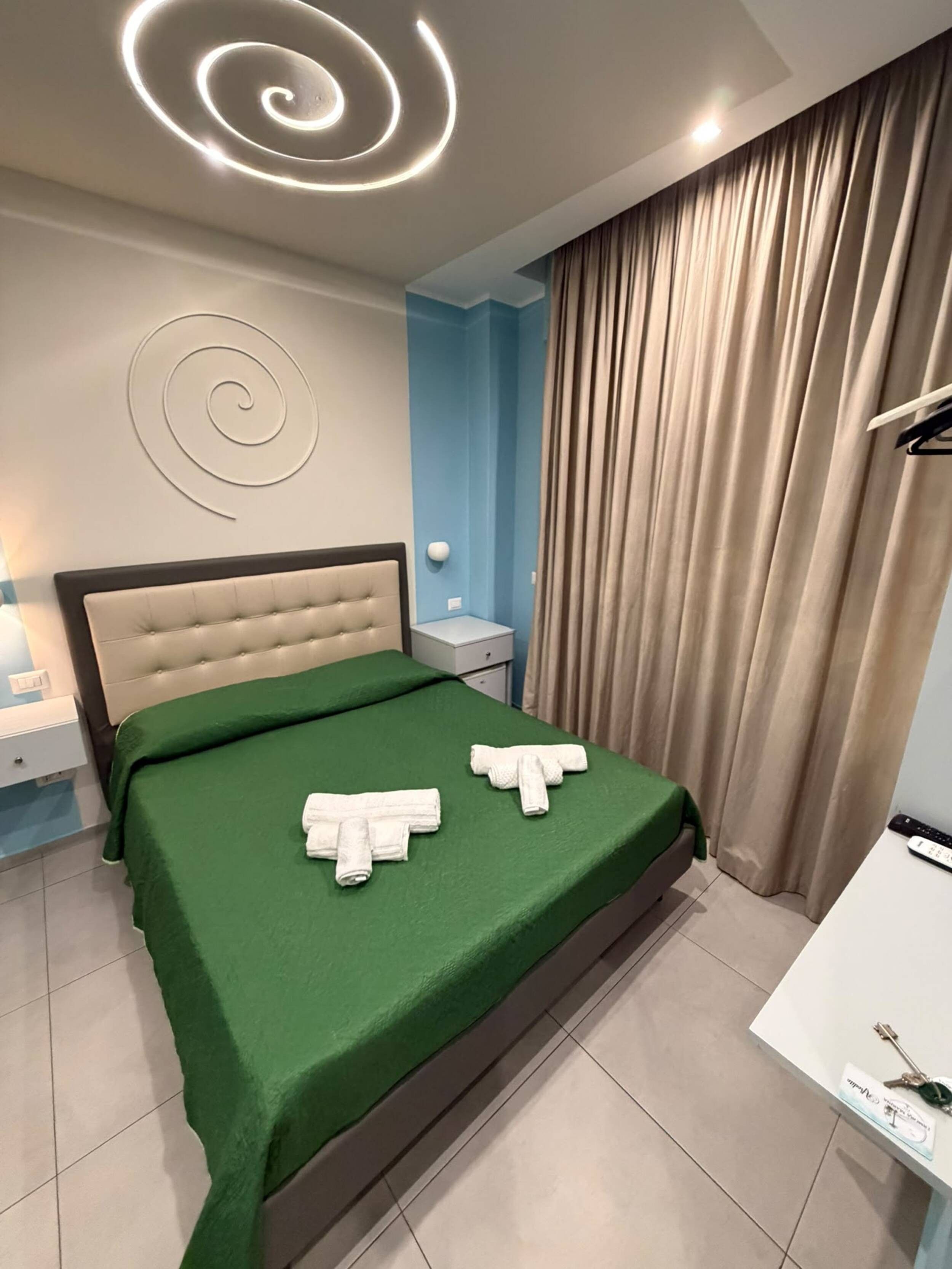 Quarto de hotel moderno com cama, mesa de cabeceira, escrivaninha e banheiro.