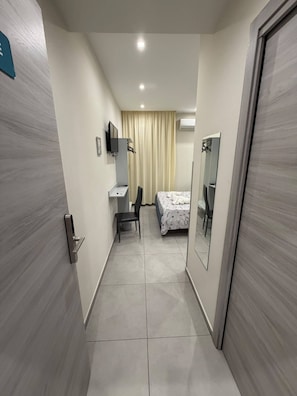 A hotel room with a bed, a desk, a chair, a television, and a mirror. - Room 'Artemide' with Balcony, Wi-Fi and Air Conditioning (piano primo)