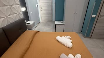 Una habitación de hotel con cama, mesita de noche, escritorio y armario.