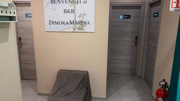 Ein Flur mit einem Schild für B&B Dimora Marina, einem Feuerlöscher und einem abgedeckten Gegenstand.