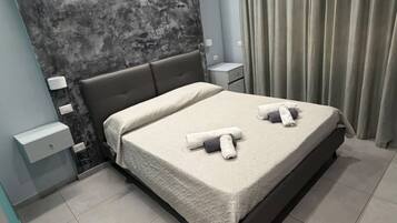 Un dormitorio moderno con una cama grande, una mesita de noche, una lámpara de pared y una cortina.