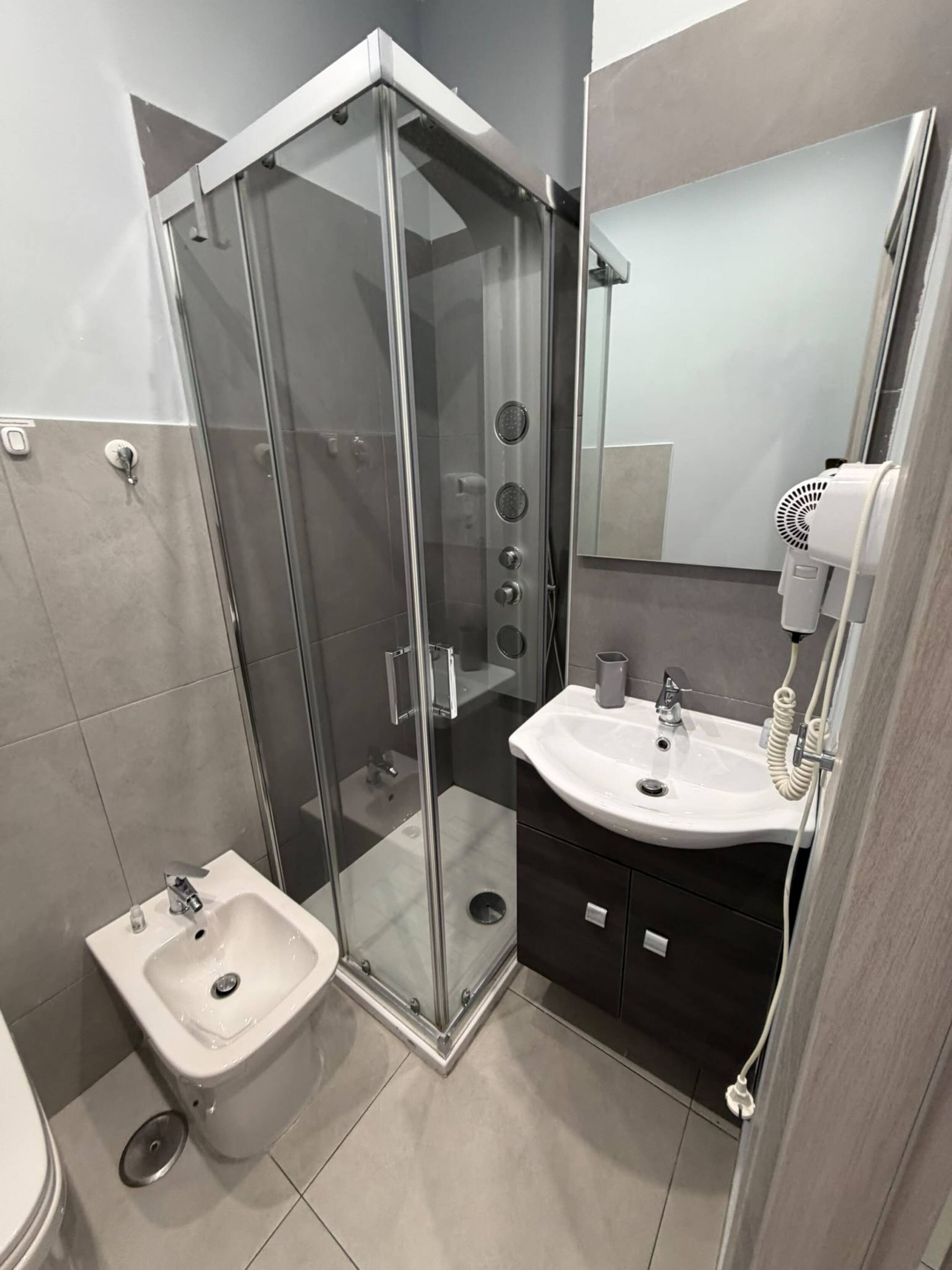 Ein modernes Badezimmer mit einer gläsernen Duschkabine, einem weißen Waschbecken und einem Bidet.