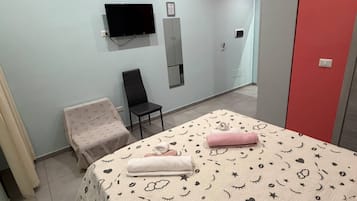 A bedroom with a bed, a chair, a TV, and a wardrobe.