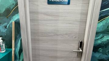 Een deur met een bord waarop 'PERSEFONE' staat en een metalen handgreep.
