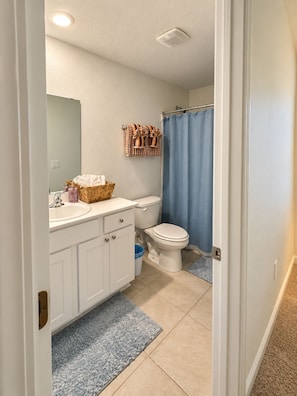 Un baño con inodoro, lavamanos y cortina de ducha.