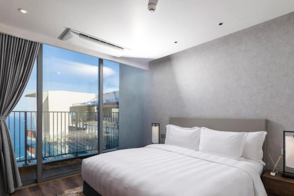 Una habitación de hotel moderna con una cama grande, vista al mar y un balcón.