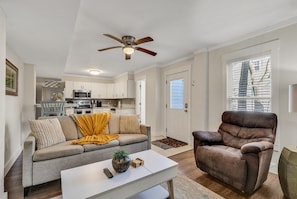 A living room with a sofa, a coffee table, a brown leather chair, and a ceiling fan.