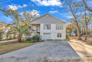 A two-story house with a garage, a front porch, and a driveway leading to the garage.