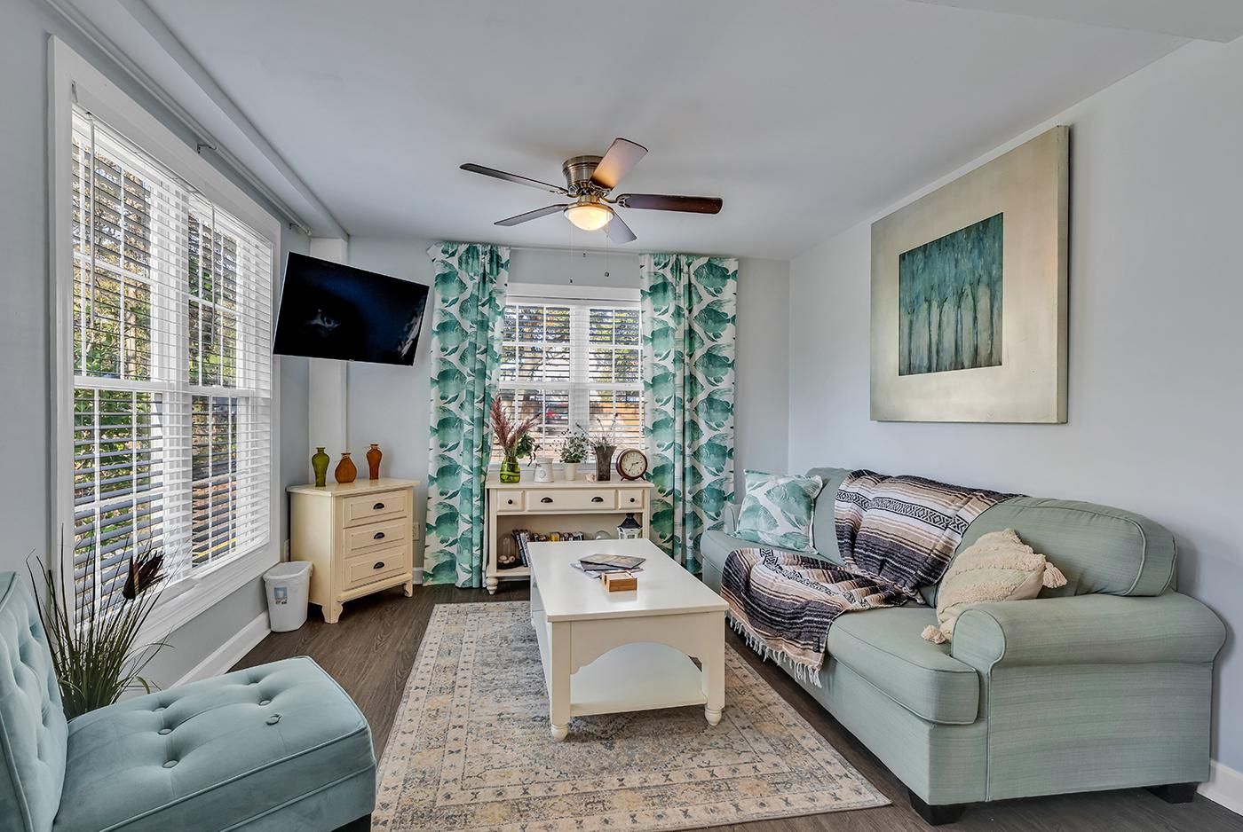 A living room with a sofa, a coffee table, a TV, and a ceiling fan.